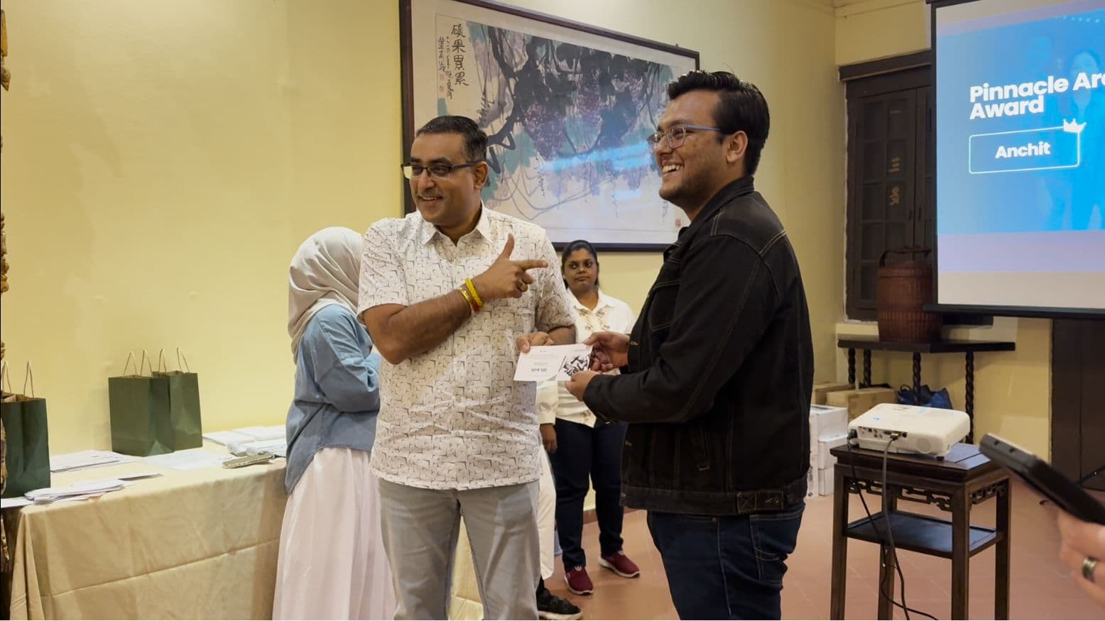 Anchit Shrivastava receiving an award, with a screen behind him reading 'Pinnacle Achievement Award — Anchit'.