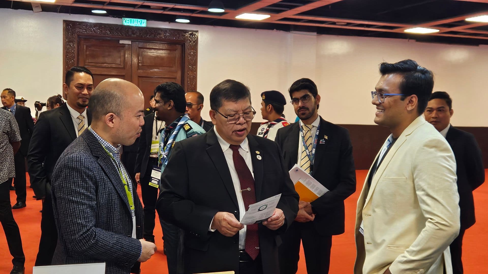 Anchit Shrivastava, in a cream blazer, smiling among dignitaries as the Speaker of Malaysia's House of Representatives reads a Joget brochure.